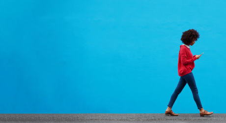 Woman walking in the bottom right hand corner of a blue backdrop